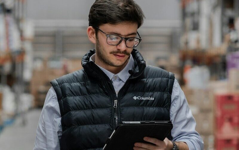 Man in vest using tablet in a warehouse