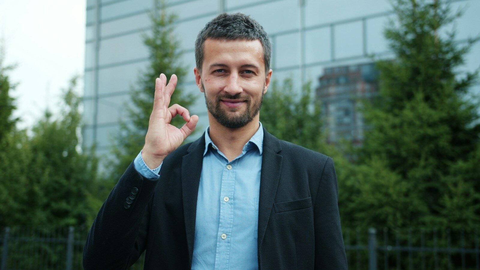 Man in suit gives okay sign with a smile