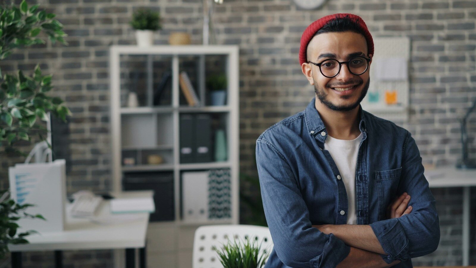 a man with glasses and a red hat standing in an office